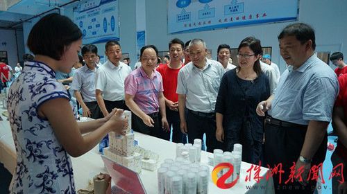 副厅长应若平在化妆品展示台前观看，与学生交谈，了解产教融合情况。